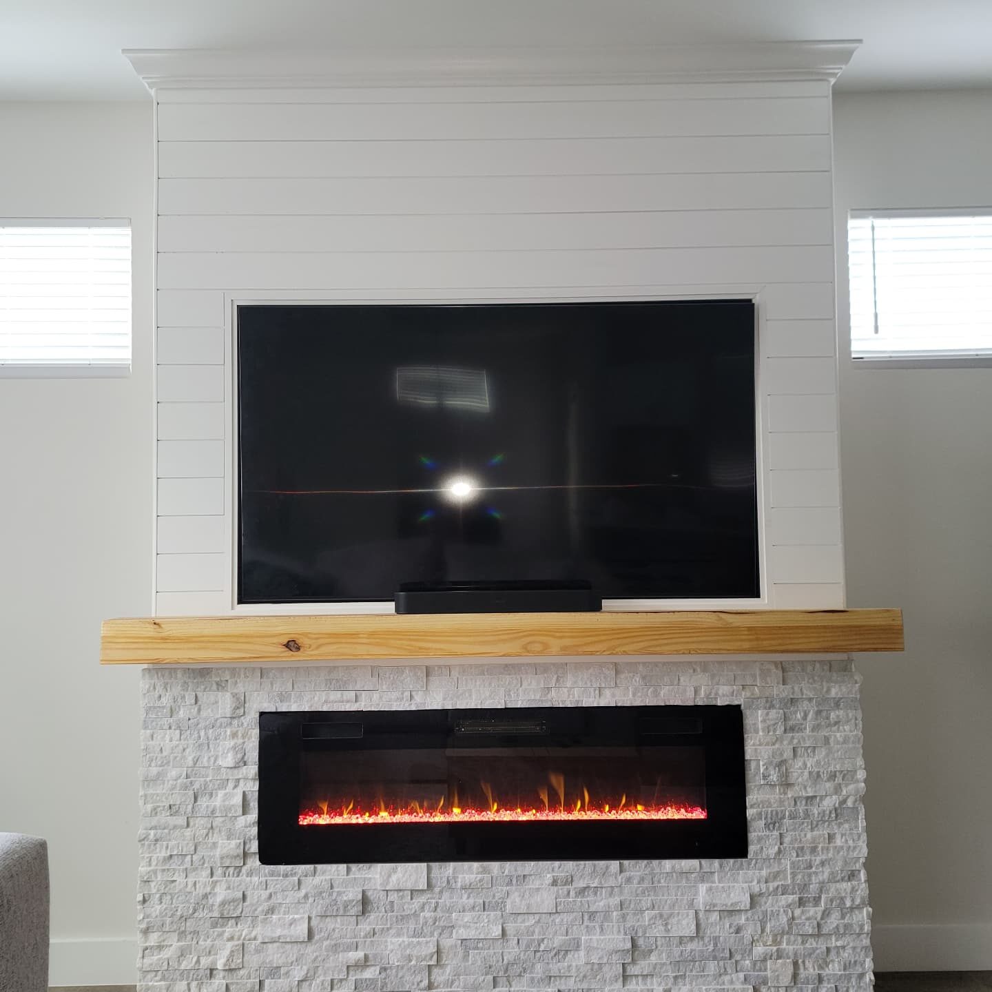 Shiplap Fireplace & TV Wall after in Downtown Orlando: framed surround, shiplap, stacked stone, wood mantel and trim